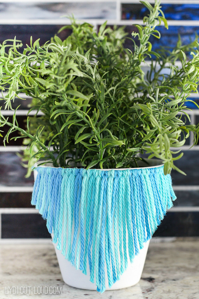 Blue and turquoise yarn wrapped around a white pot and cut into a v shape.