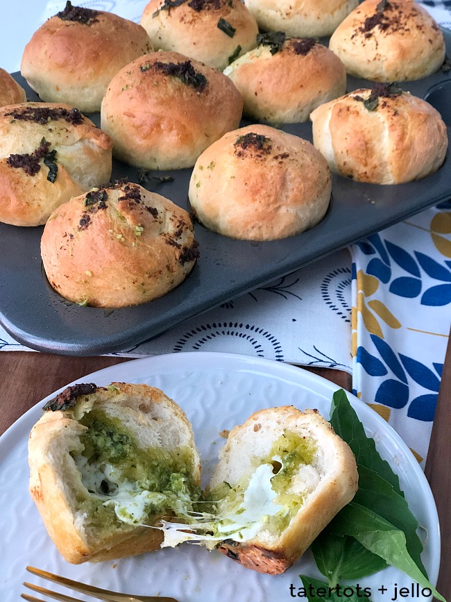 Stuffed Cheesy Mozzarella Pesto Rolls are an easy recipe to whip up using pre-made Rhodes dough. Warm fragrant rolls are stuffed with gooey Mozzarella and Parmesan cheese, pesto and basil. It's the perfect compliment to an Italian Dinner OR a great lunch on it's own! 