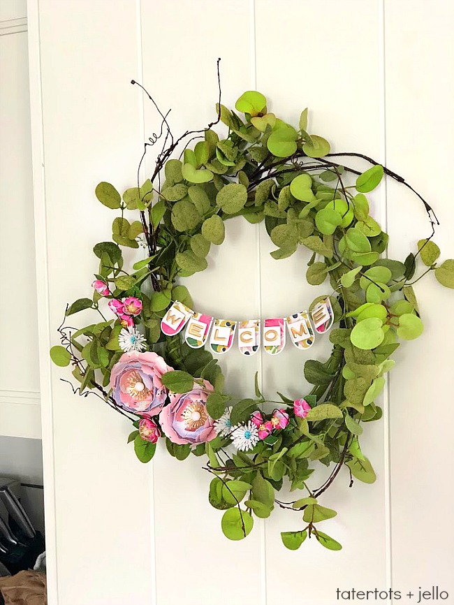 Make a WELCOME Banner Wreath. Combine the beautiful elements of greenery with paper flowers and a paper banner for a wreath that welcomes everyone! 