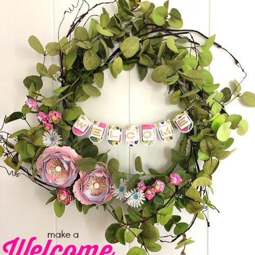 Make a WELCOME Banner Wreath. Combine the beautiful elements of greenery with paper flowers and a paper banner for a wreath that welcomes everyone! 