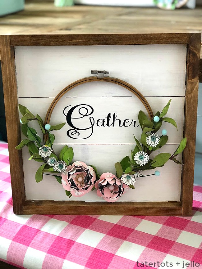 Make an Autumn Framed Embroidery Hoop Gather Wall Hanging. Create a beautiful Fall Wall Hanging with a frame, an embroidery hoop, vinyl letters and paper flowers. Hang it on your front door or a wall to welcome Autumn to your home! 