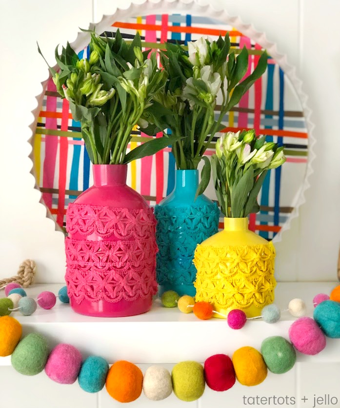 Anthropologie-Inspired Colorful Spring Vases DIY. Take simple jars, add spray paint and trim to create a beautiful centerpiece for a fraction of the cost! 
