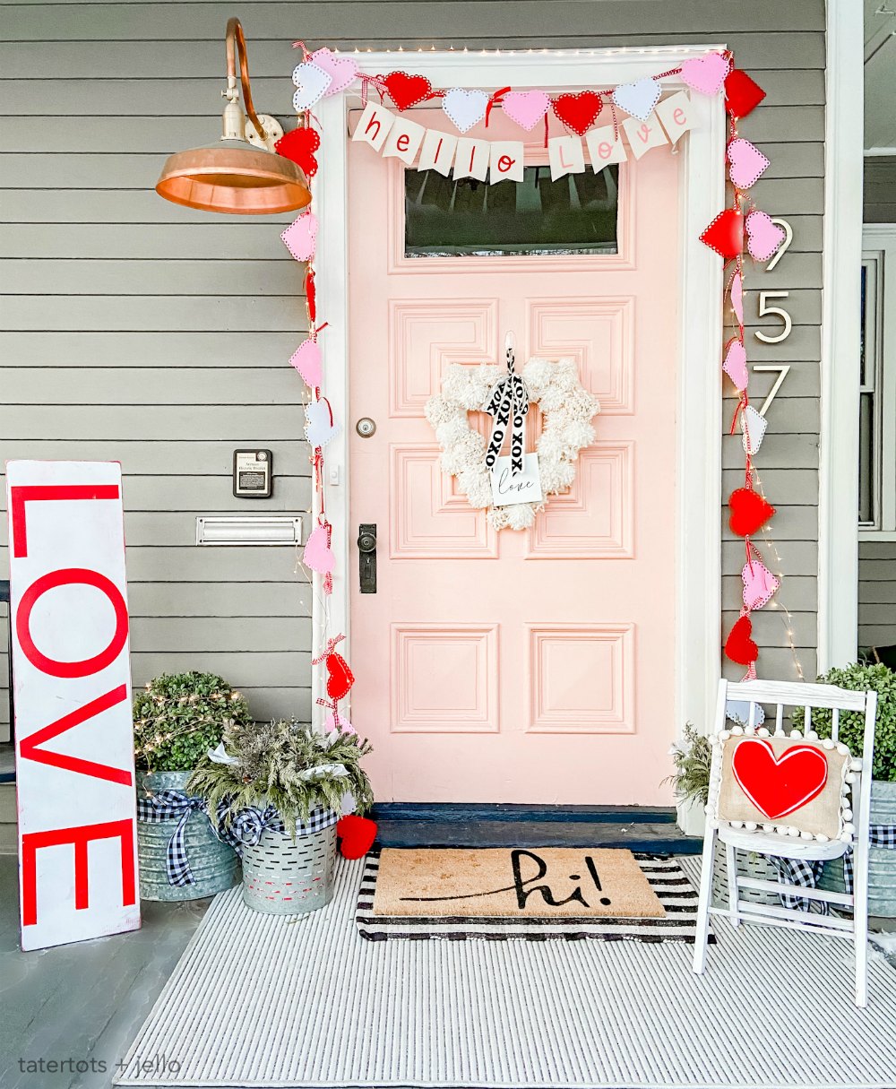 Pink and Red Valentine's Porch. Make a DIY garland, sign, banner, pillow and wreath to create a bright and colorful porch for Valentine's Day!