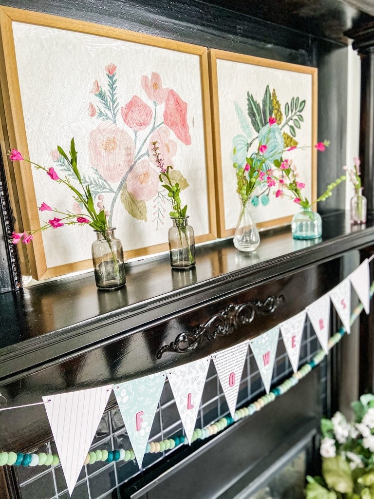 Simple Spring Flower Mantel. Colorful flower art, sweet vases of flowers and a handmade banner are easy to put together to bring some Spring sunshine to your mantel.