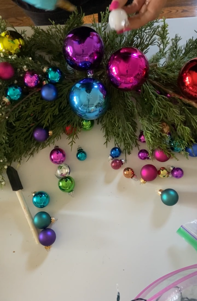 Colorful Holiday Embroidery Hoop Ornament Wreath. Create a stunning holiday wreath with inexpensive ornaments, faux greens and a simple embroidery hoop. 