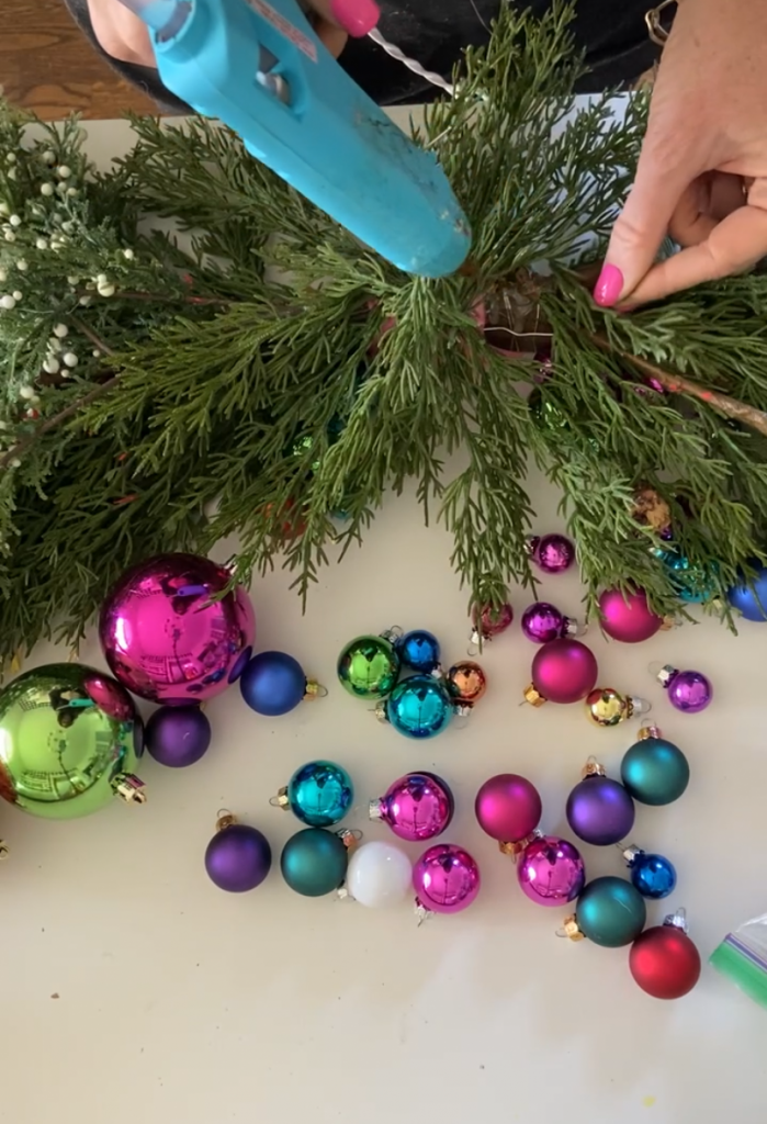 Colorful Holiday Embroidery Hoop Ornament Wreath. Create a stunning holiday wreath with inexpensive ornaments, faux greens and a simple embroidery hoop. 