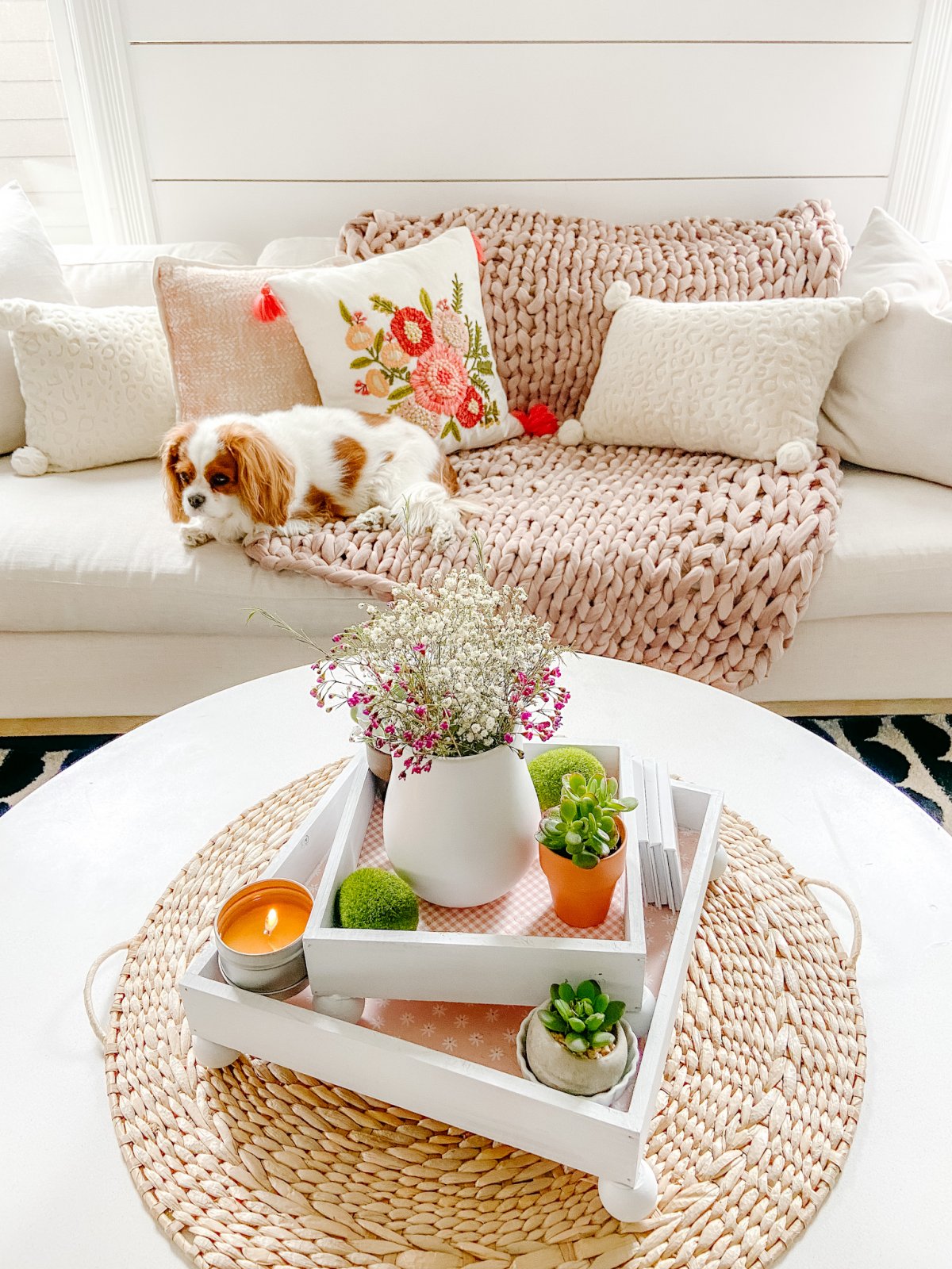 white square frames, lined with scrapbook paper and layered with a vase of flowers at the top, a candle and potted succulents. 