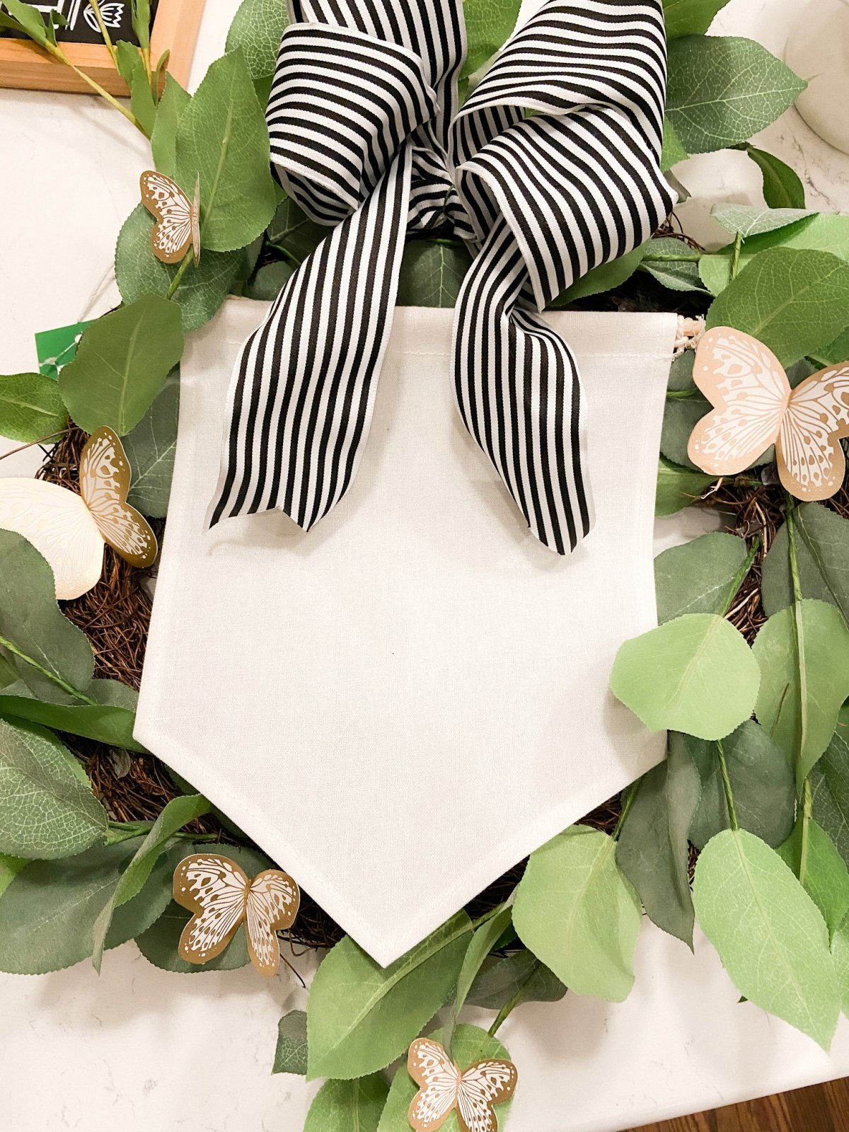 Spring Butterfly Pennant Wreath. Celebrate spring by making this simple wreath with butterflies cut out of cardstock and a big pennant in the middle and a spring saying!