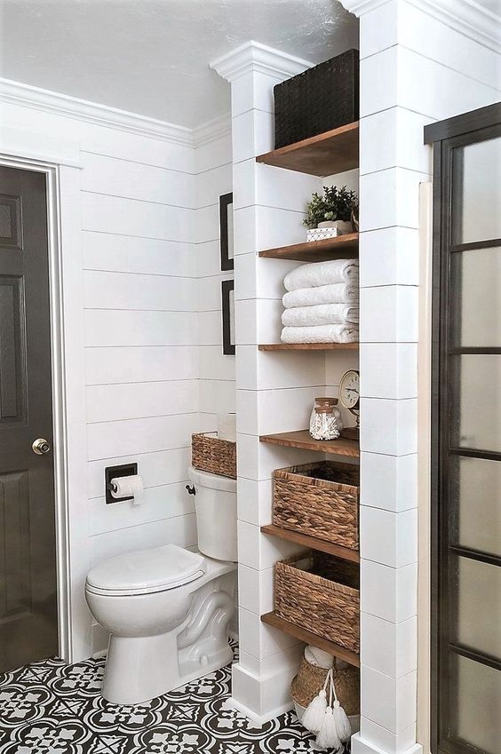 Shiplap bathroom with open shelves built into the wall next to the shower.