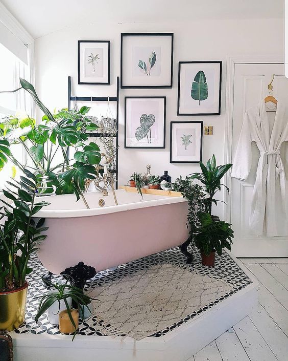 Pink clawfoot tub on a pedestal set at an angle surrounded by plants. 