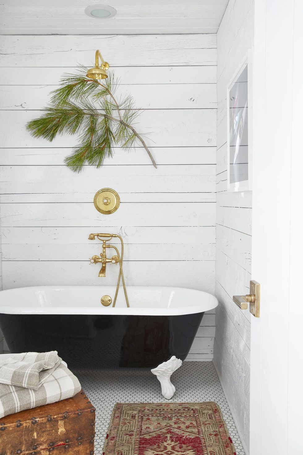 Simple shiplap walls with a back clawfoot tub and brass fixtures. 