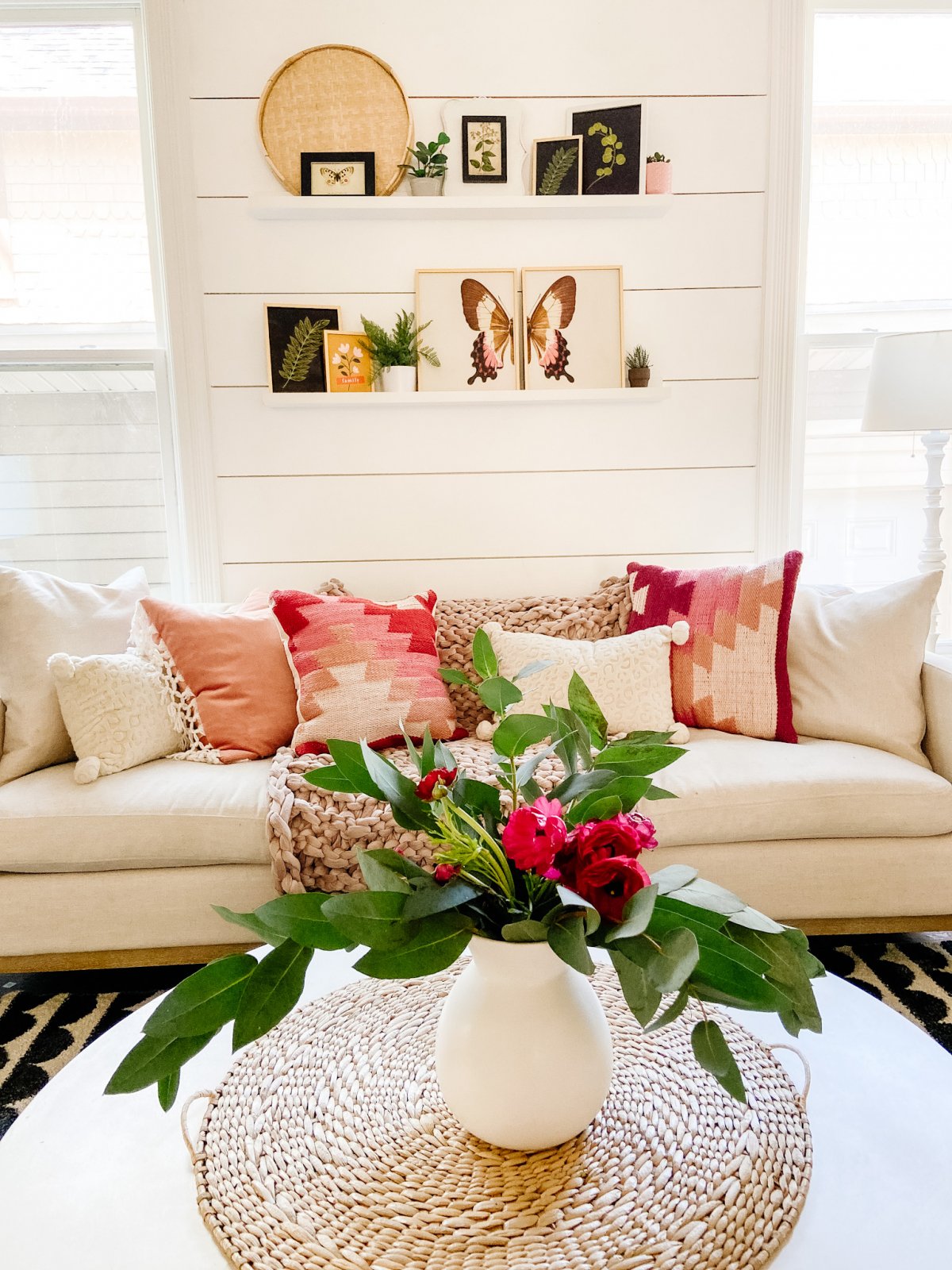 Butterfly and botanical prints on two shelves with plants.