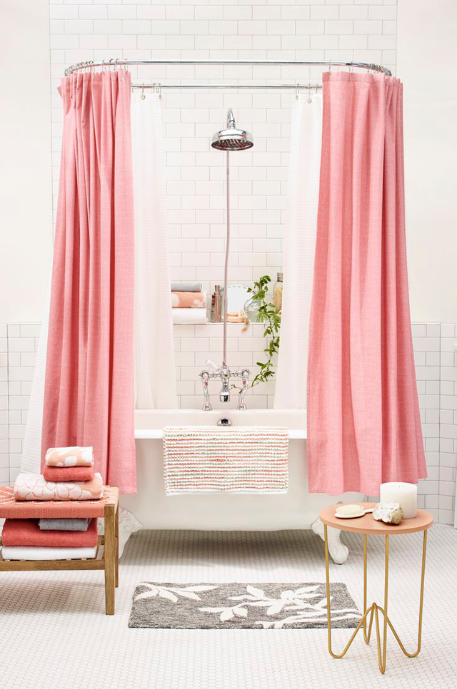 White clawfoot tub with a pink shower curtain in a white bathroom. 