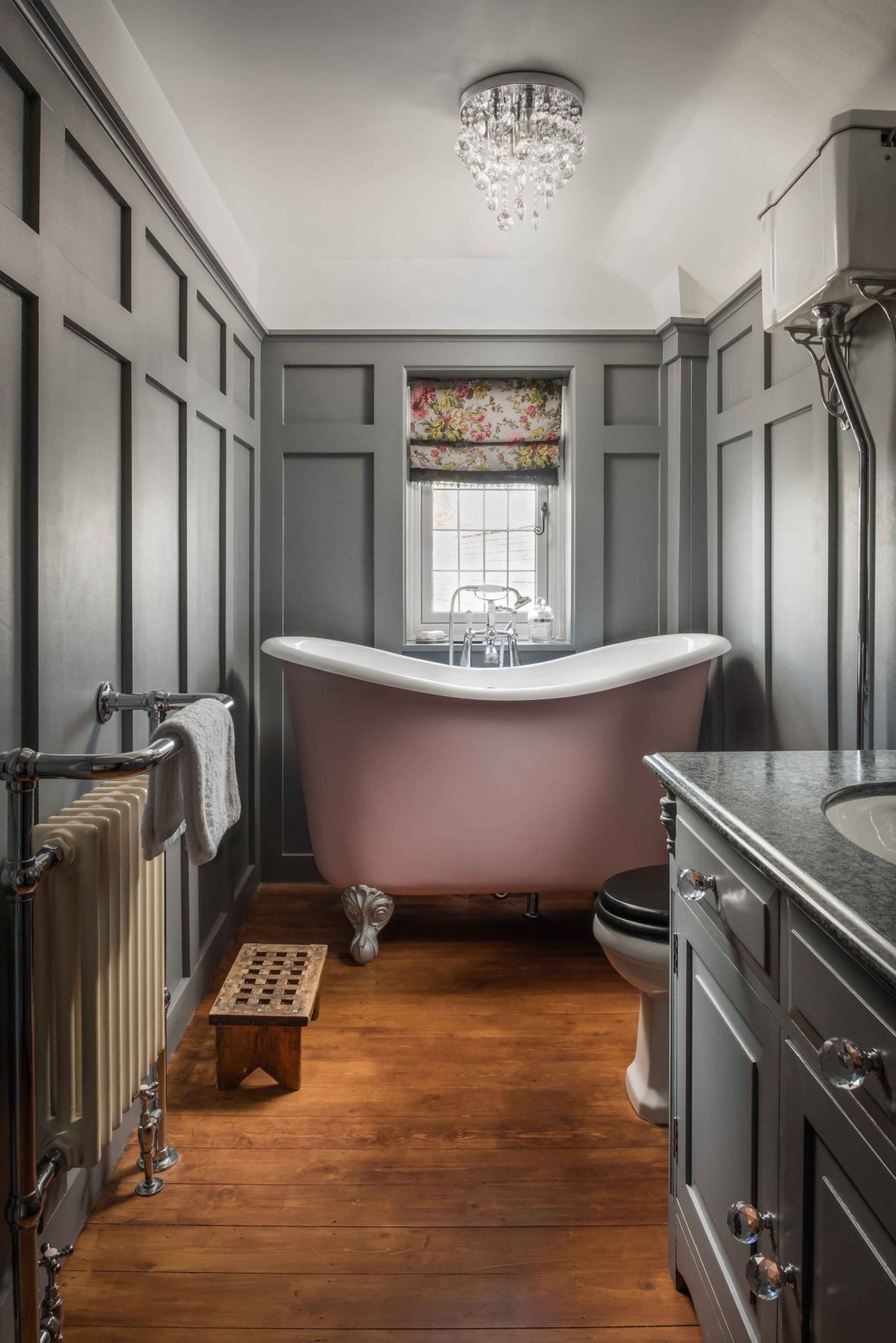 A pink tubby tub which is a higher height and can fit in a small room. Grey wainscoting in a traditional bathroom remodel 