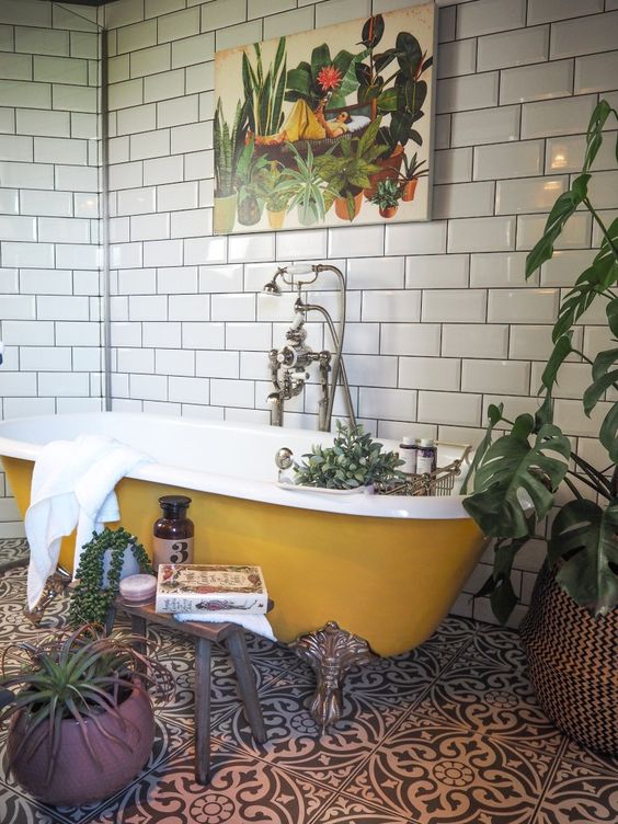 Yellow clawfoot tub with black and white patterned tile in a victorian bathroom remodel 