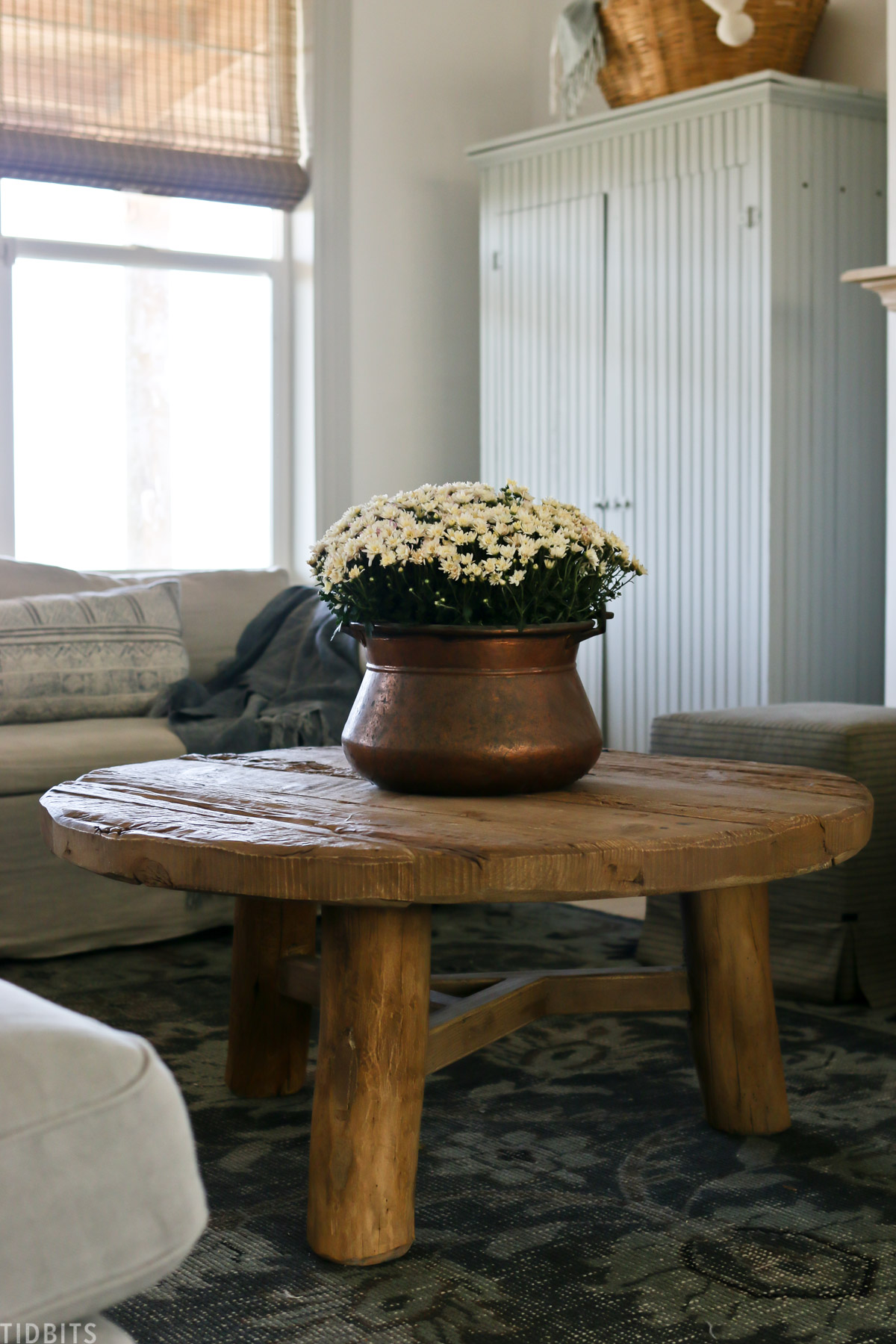 Vintage copper vessel with live mums on a wood coffee table for easy early fall decor. 