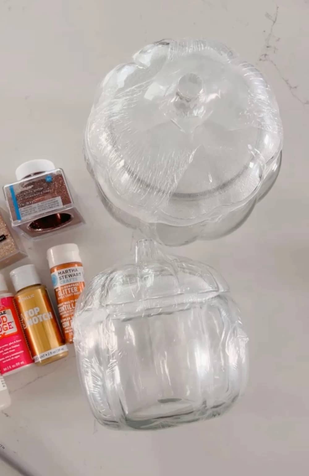 Pottery Barn Inspired Amber Pumpkin Cloches. Turn inexpensive glass pumpkin containers into high end looking cloches by painting and adding glitter! 