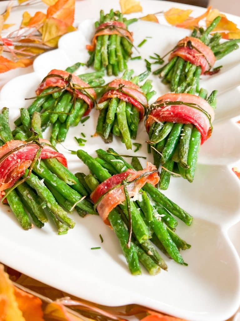 Bacon-Wrapped Green Bean Bundles. The perfect side dish for Thanksgiving or any holiday, these delicate green beans are layered with a garlic glaze and wrapped in crispy bacon with a chive bow. 