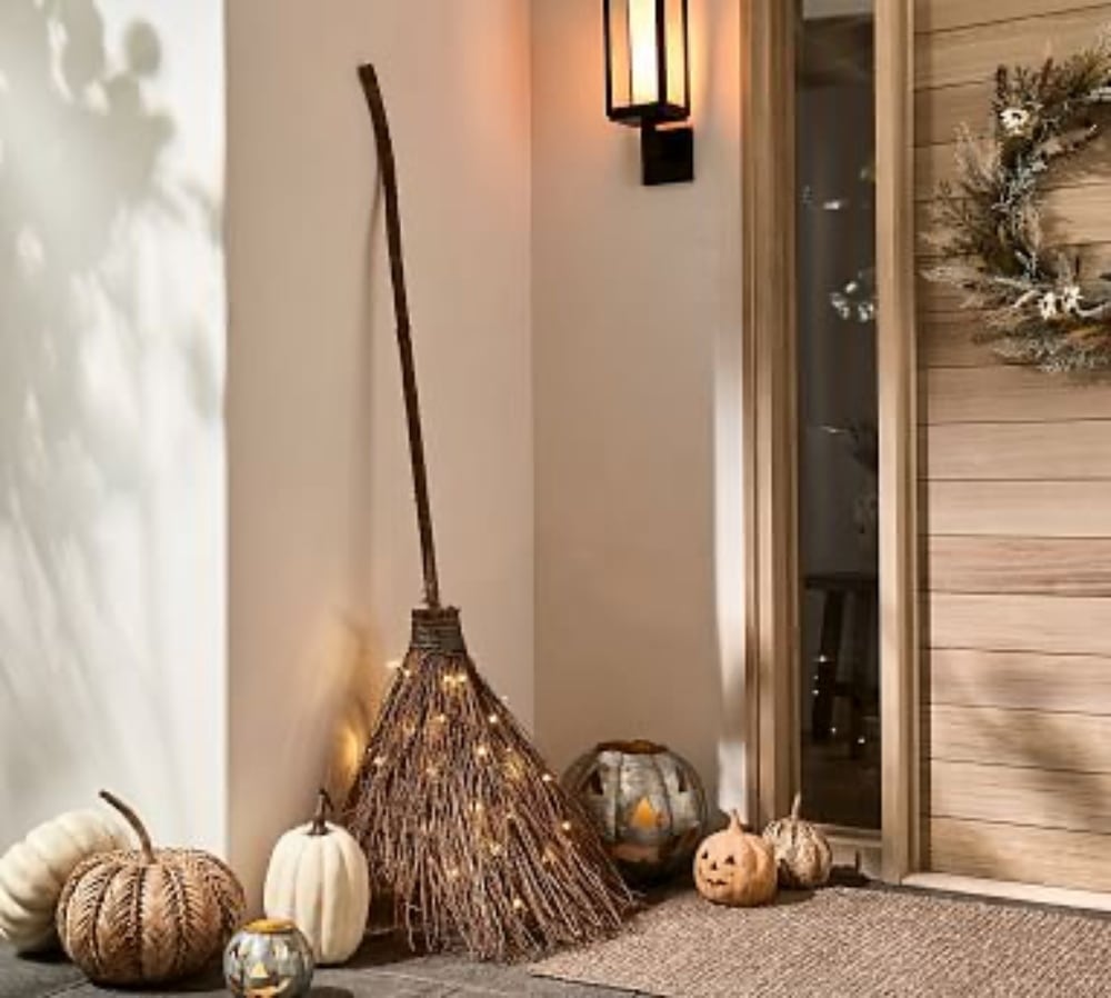 Halloween Witches Broom Wreath. Cast a welcoming spell on visitors this Halloween by creating a delightful witch porch. A glowing witches broom is a whimsical wreath alternative. Battery operated shimmering lights will light the way for guests. This is a hack on the Pottery Barn version for a fraction of the price!