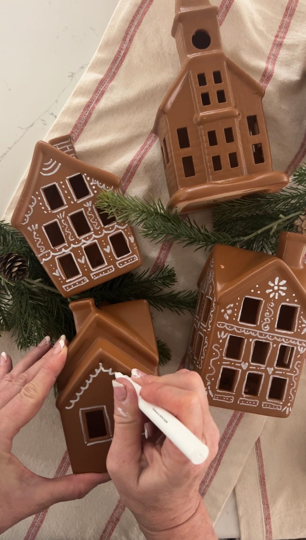 Turn a Ceramic Village into a Gingerbread Village. Revamp a plain ceramic Christmas village into a festive delight using spray paint, a white paint pen, and puffy paint. 