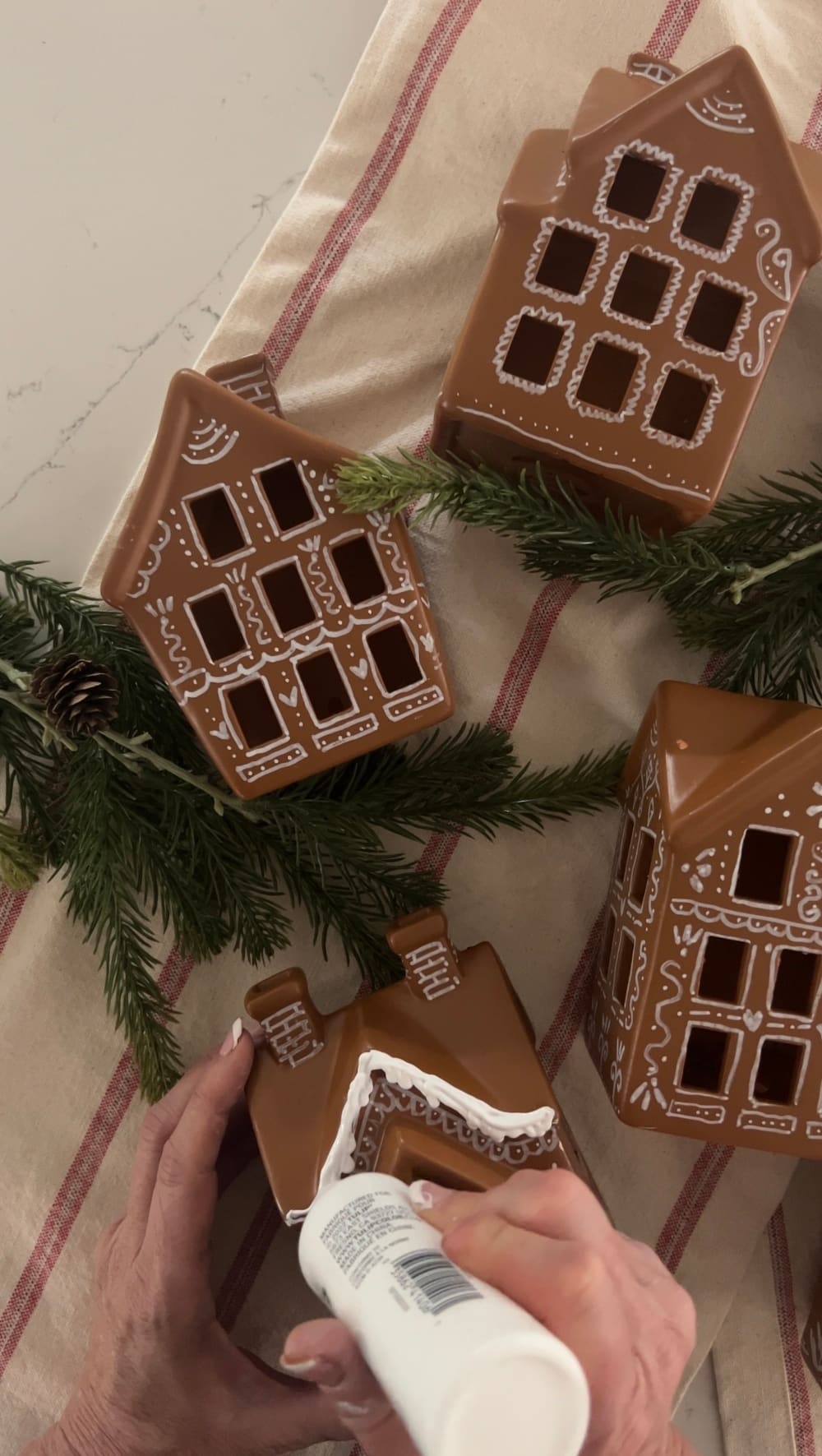 Turn a Ceramic Village into a Gingerbread Village. Revamp a plain ceramic Christmas village into a festive delight using spray paint, a white paint pen, and puffy paint. 