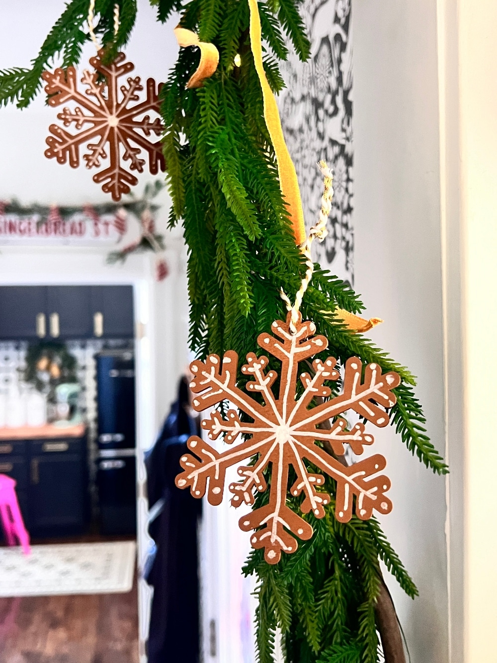 DIY Faux Gingerbread Cookie Ornaments. Transform simple wood snowflake ornaments into charming faux gingerbread cookies for a decoration that adds a touch of sugary sweetness to your holiday decor.