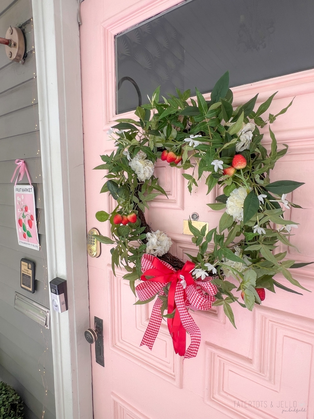 DIY Summer Strawberry Wreath. Create a charming summer strawberry-themed wreath by combining faux strawberries and flowers, lush greenery, and a red bow for a delightful way to decorate your front door.