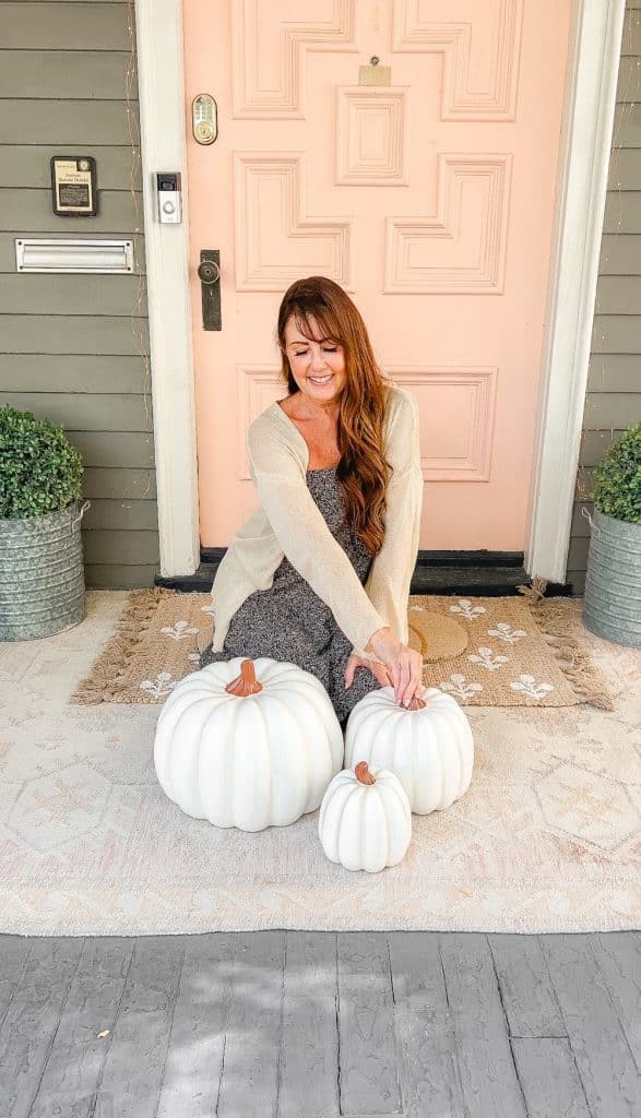 Candy Corn-Colored Fall Porch with Stacked Pumpkins. Create a warm, inviting fall porch with the coolest stacked pumpkins, a vibrant DIY wreath, and layered plaid rugs for a festive, seasonal touch.