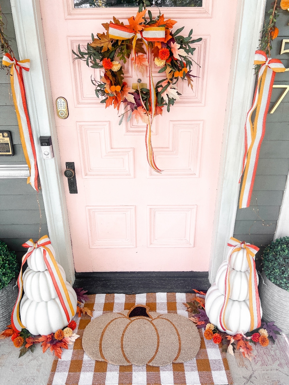 Candy Corn-Colored Fall Porch with Stacked Pumpkins. Create a warm, inviting fall porch with the coolest stacked pumpkins, a vibrant DIY wreath, and layered plaid rugs for a festive, seasonal touch.