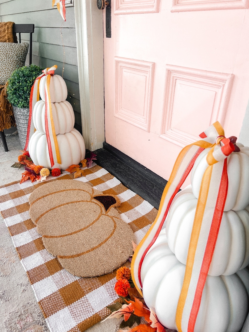 Candy Corn-Colored Fall Porch with Stacked Pumpkins. Create a warm, inviting fall porch with the coolest stacked pumpkins, a vibrant DIY wreath, and layered plaid rugs for a festive, seasonal touch.