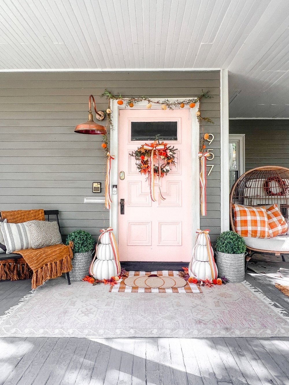 Candy Corn-Colored Fall Porch with Stacked Pumpkins. Create a warm, inviting fall porch with the coolest stacked pumpkins, a vibrant DIY wreath, and layered plaid rugs for a festive, seasonal touch.