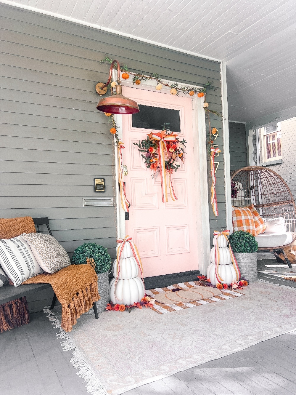 Candy Corn-Colored Fall Porch with Stacked Pumpkins. Create a warm, inviting fall porch with the coolest stacked pumpkins, a vibrant DIY wreath, and layered plaid rugs for a festive, seasonal touch.