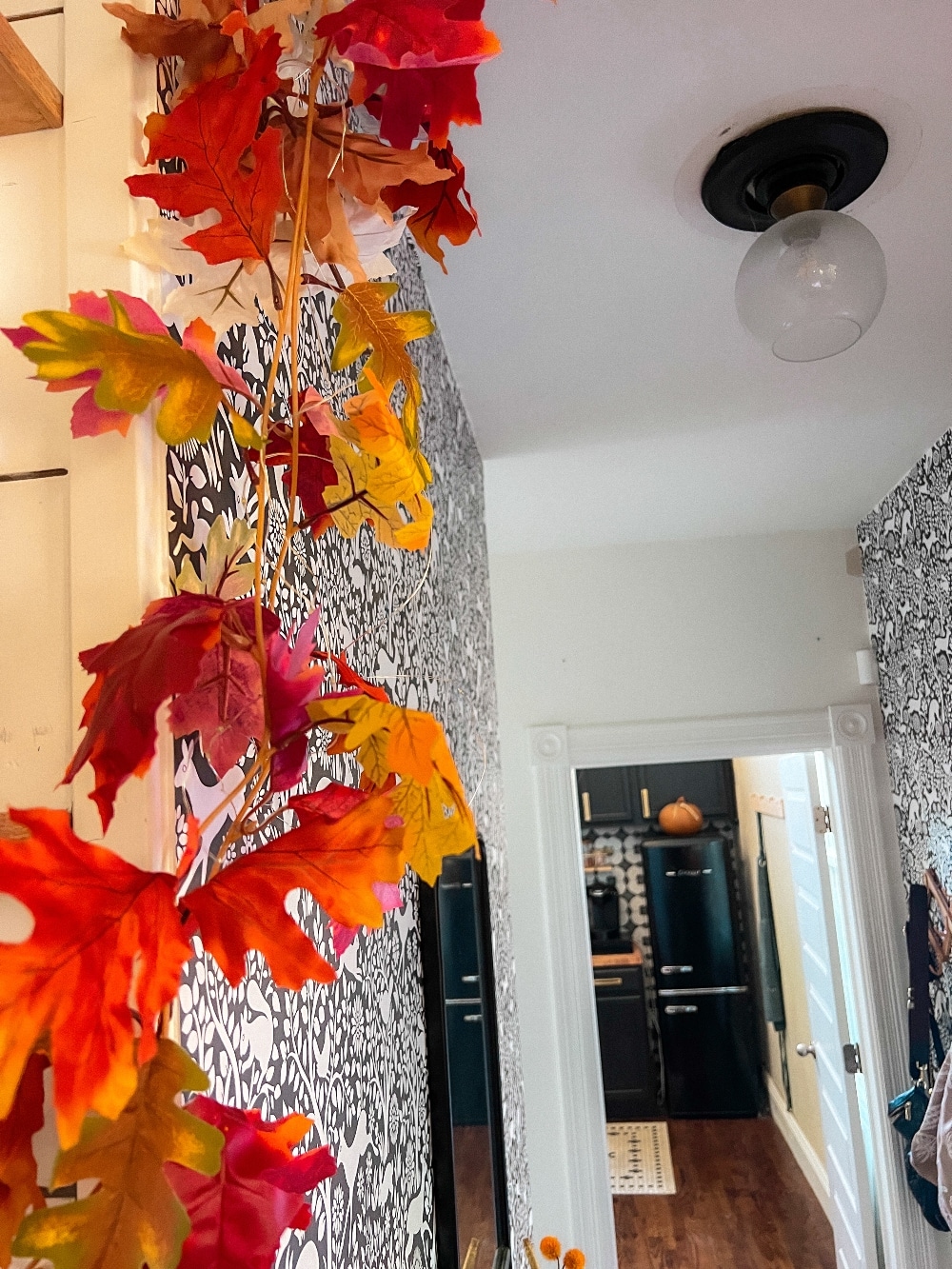 Easy Fall Over the Door Lighted Garland. Create an easy and festive fall over-the-door garland using inexpensive leaf garlands, twinkle lights, and a shower curtain rod, perfect for autumn decor.