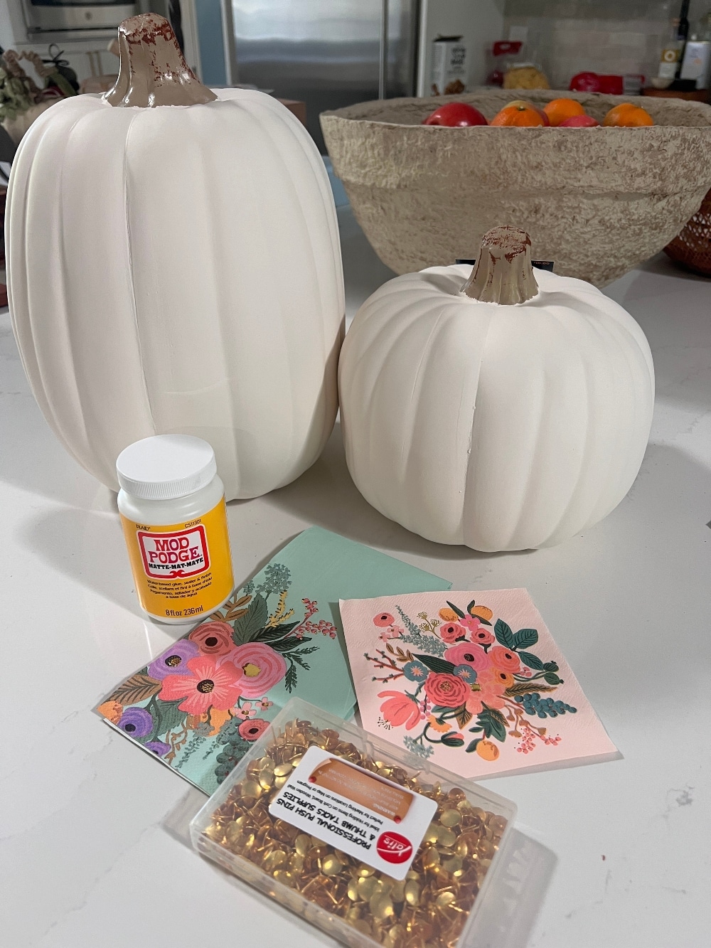 DIY No-Carve Monogram Pumpkin. Create a stylish, no-carve monogram pumpkin for fall using gold thumbtacks and decoupaged florals cut from napkins—perfect for adding a personal touch to your seasonal decor!