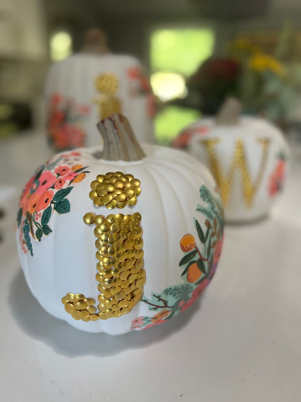 DIY No-Carve Monogram Pumpkin. Create a stylish, no-carve monogram pumpkin for fall using gold thumbtacks and decoupaged florals cut from napkins—perfect for adding a personal touch to your seasonal decor!