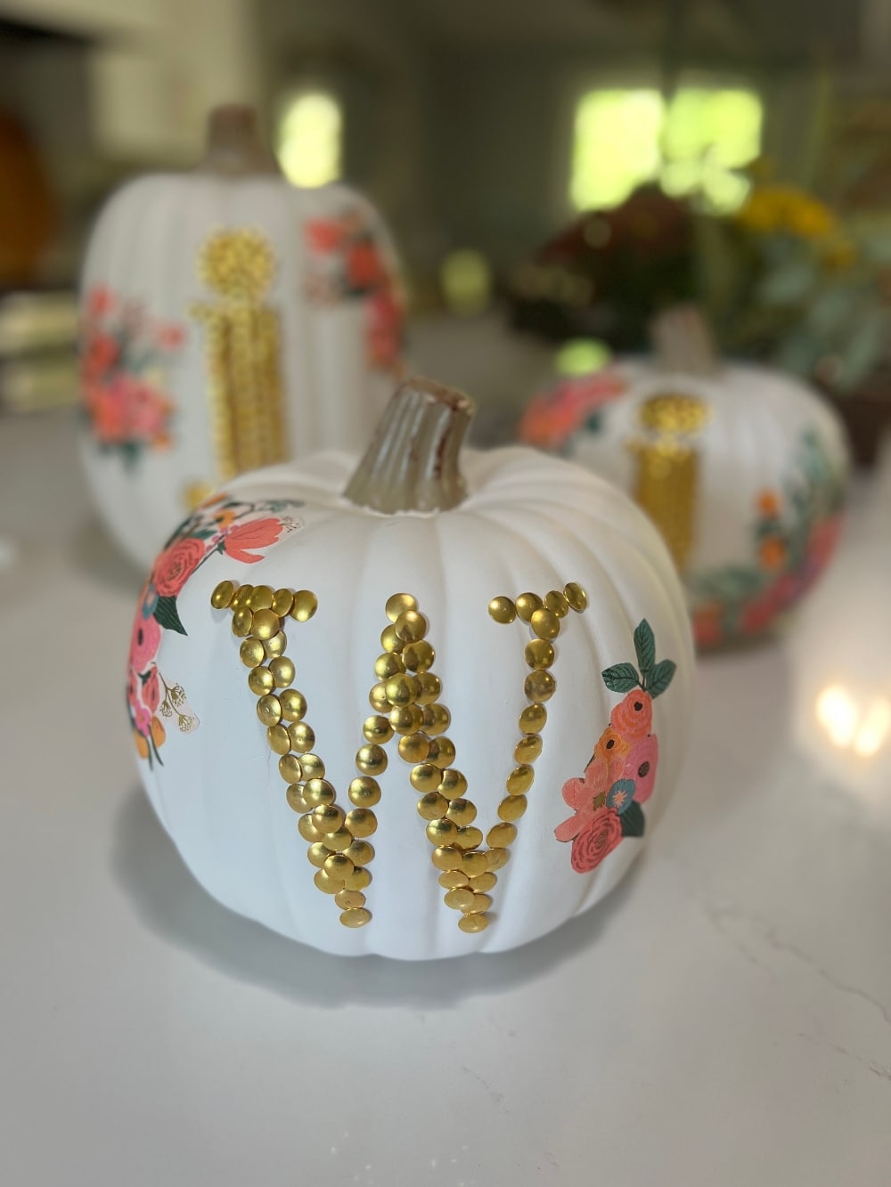 DIY No-Carve Monogram Pumpkin. Create a stylish, no-carve monogram pumpkin for fall using gold thumbtacks and decoupaged florals cut from napkins—perfect for adding a personal touch to your seasonal decor!