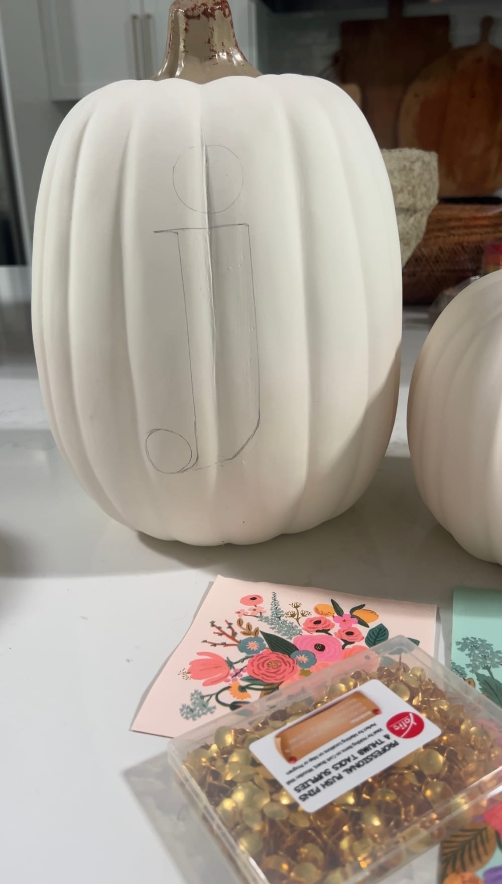 DIY No-Carve Monogram Pumpkin. Create a stylish, no-carve monogram pumpkin for fall using gold thumbtacks and decoupaged florals cut from napkins—perfect for adding a personal touch to your seasonal decor!