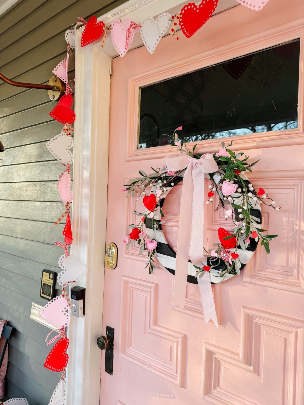 A Festive and Cozy Valentine’s Day Porch. A DIY Valentine’s porch with a striped heart wreath, felt banners, cozy pillows, and festive decor.