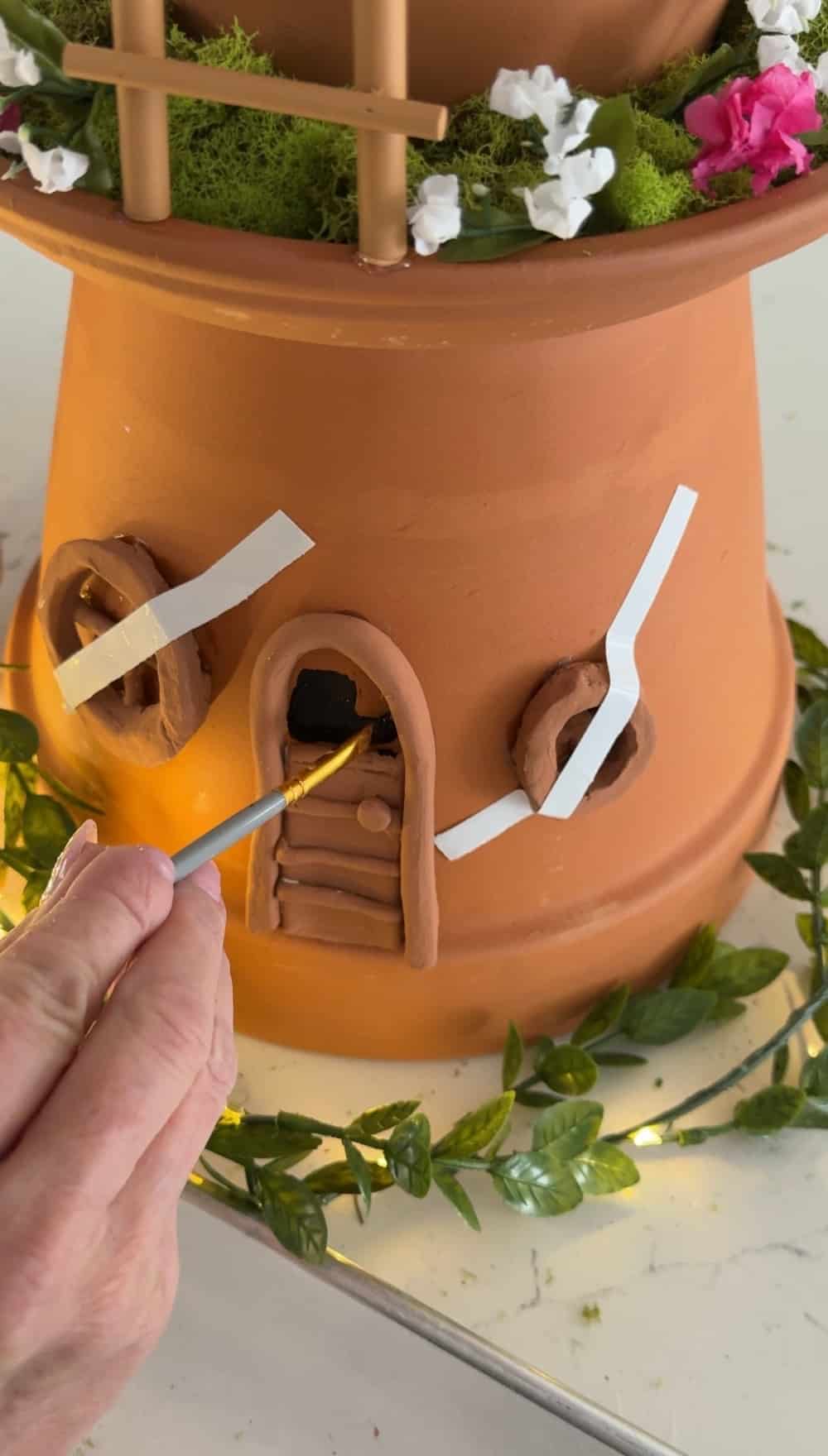 DIY Terra Cotta Pot Fairy Garden – A Magical Spring Craft. Create a whimsical stacked terra cotta fairy garden with clay doors, moss, and magical miniatures to add charm to your spring porch!
