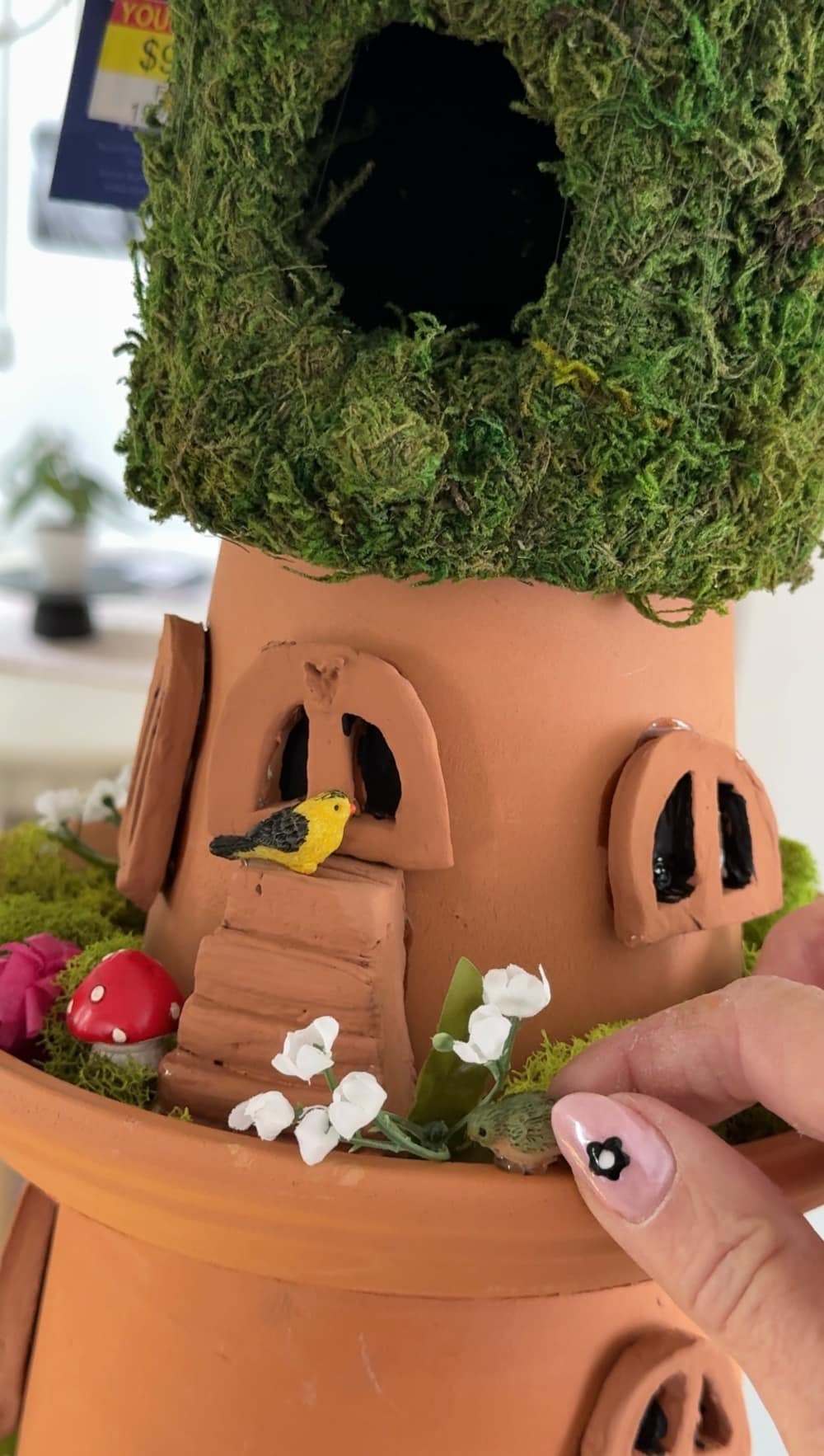DIY Terra Cotta Pot Fairy Garden – A Magical Spring Craft. Create a whimsical stacked terra cotta fairy garden with clay doors, moss, and magical miniatures to add charm to your spring porch!